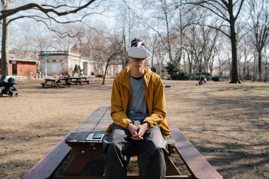 Free Man in park wearing virtual reality headset, enjoying a modern digital experience outdoors. Stock Photo