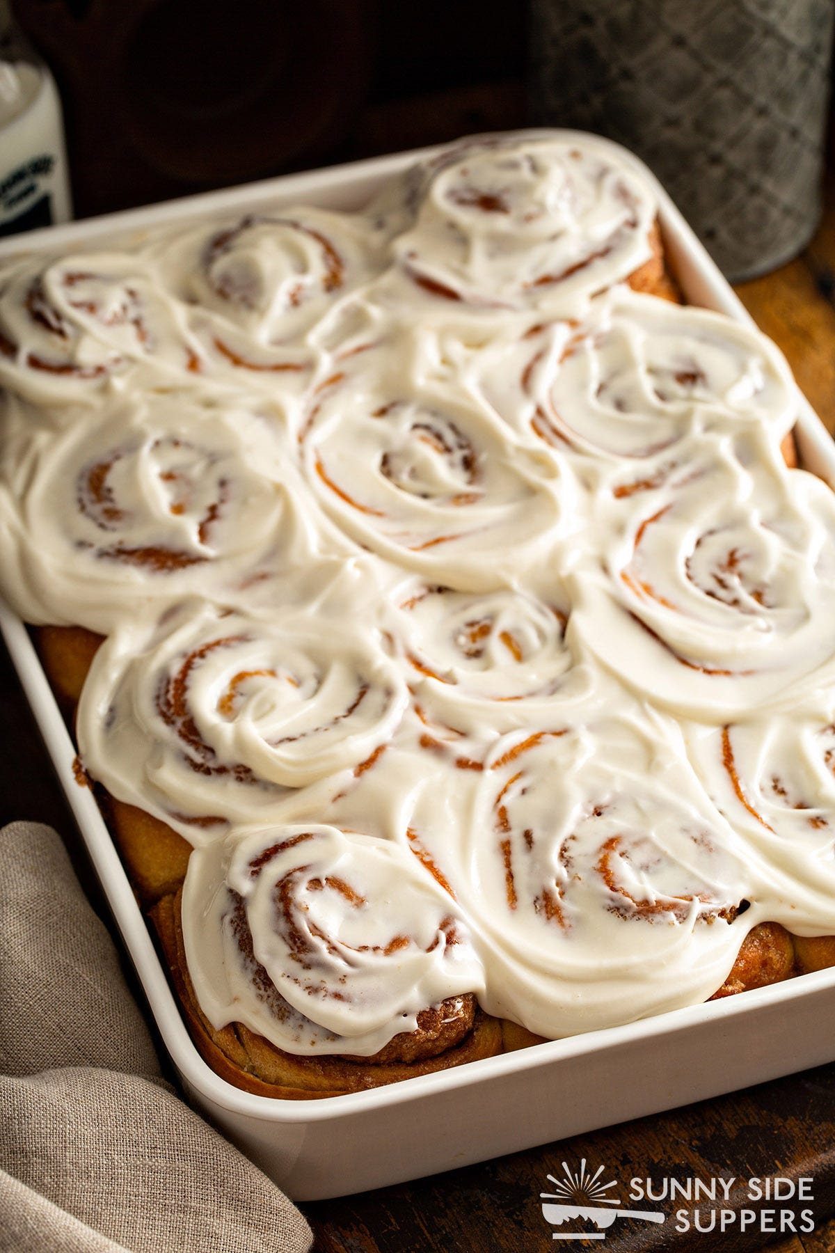 A baking pan filled with frosted cinnamon rolls.
