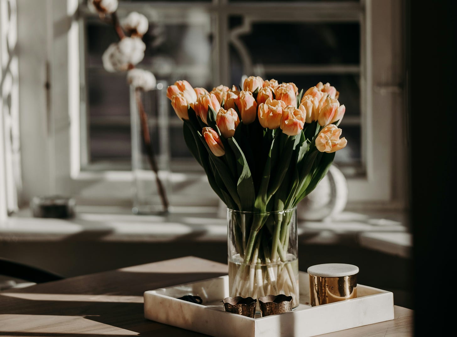 Uma mesa com um vaso de tulipas beges em destaque