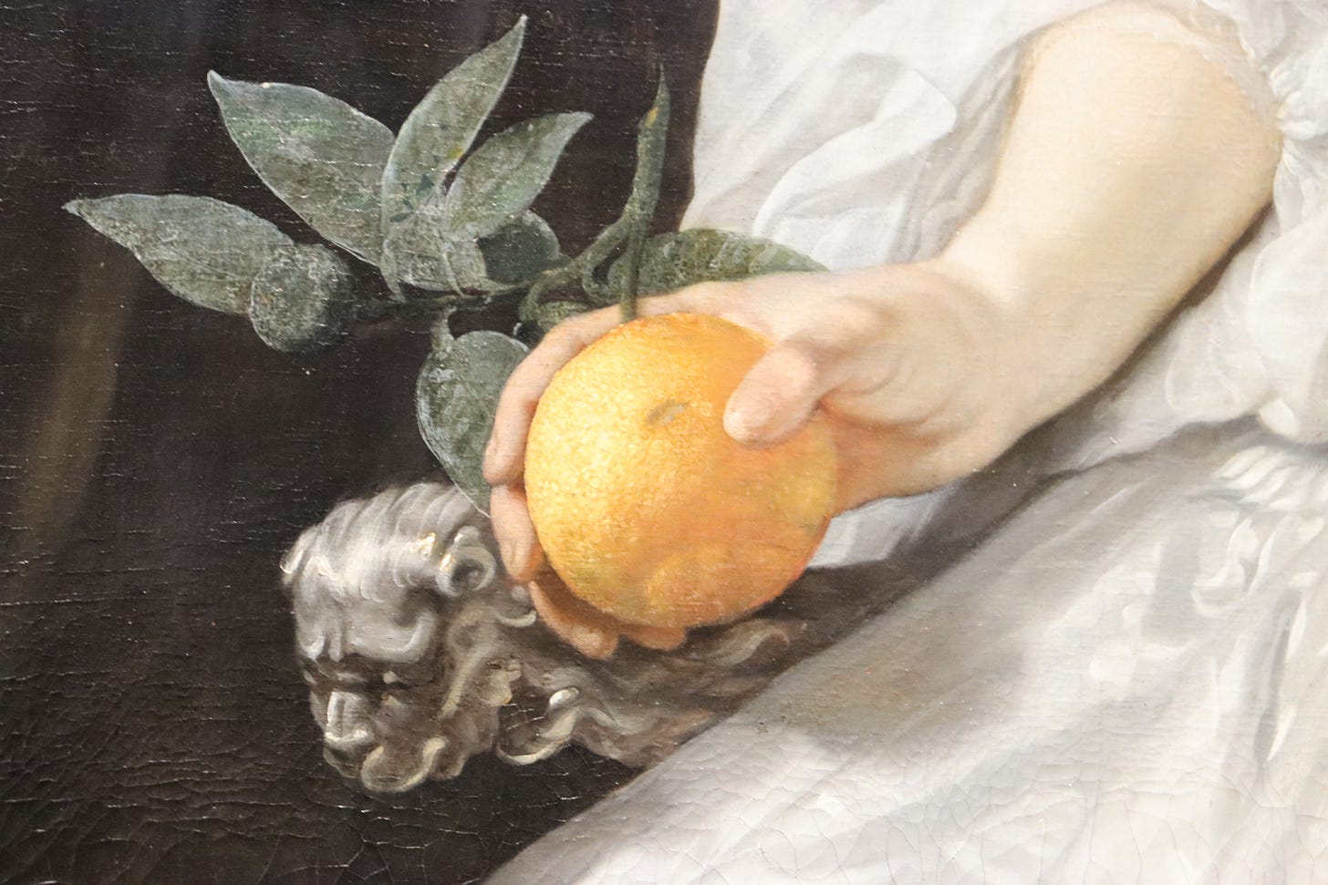 Closeup of a woman's hand holding an orange, from a painting in the Rijksmuseum's collection