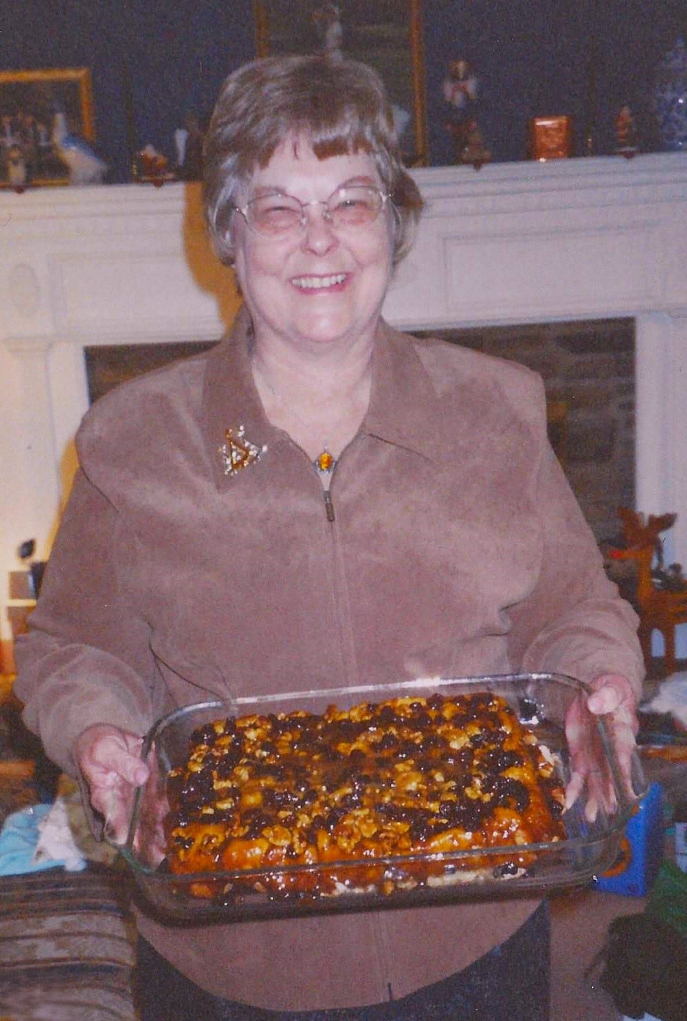 A 60-something woman beams as she shows off a pan of homemade sticky buns