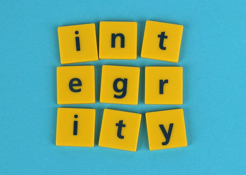 Graphic image on blue background showing the letters of INTEGRITY in yellow tiles on 3 rows: I  N T on the top row, E G R on the middle row, I T Y on the bottom row.