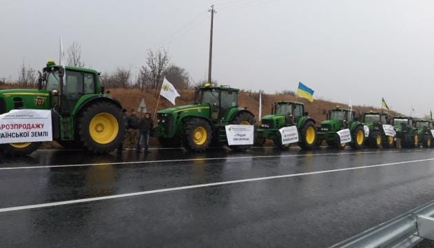 A row of tractors on a road Description automatically generated