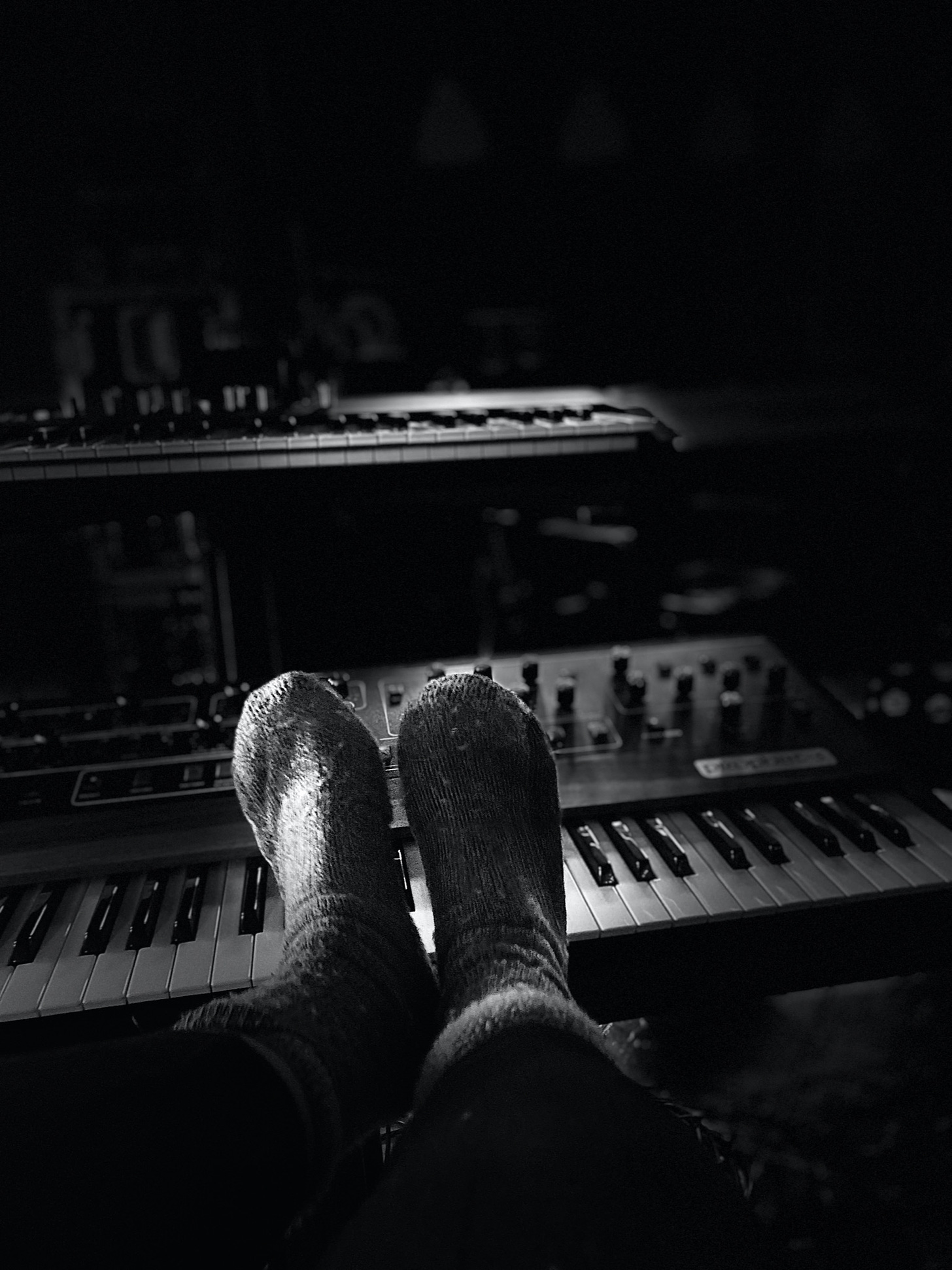 A picture at night showing Suzy's feet covered in thick wolley socks and her two synthesisers