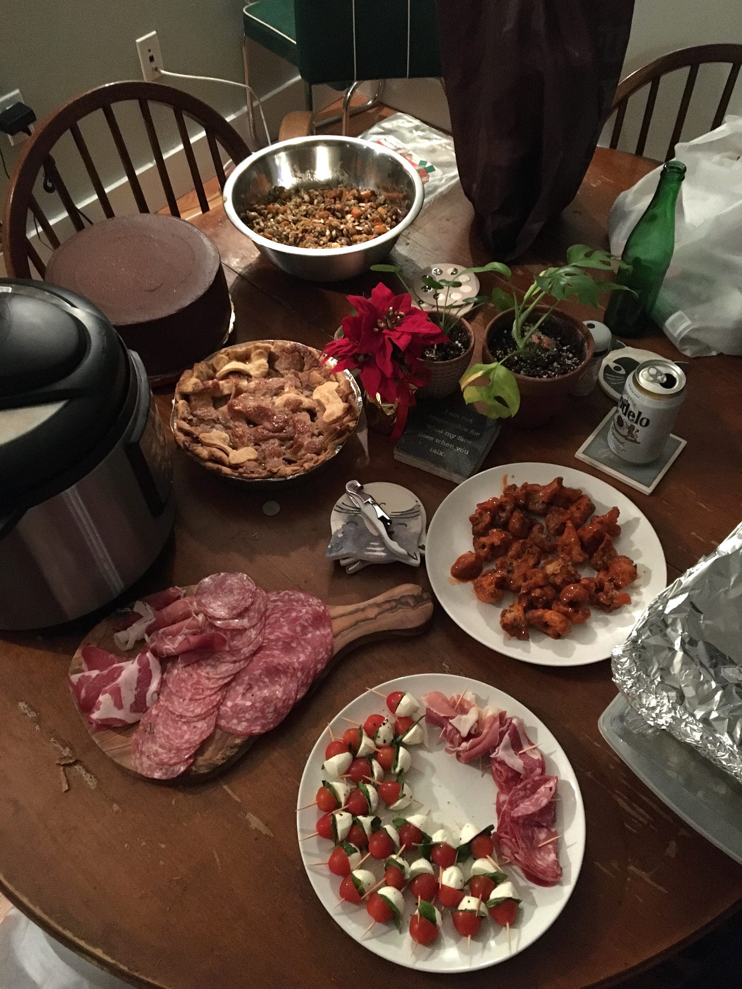 dining table with caprese skewers, buffalo cauliflower, pie, squash salad, and charcuterie board