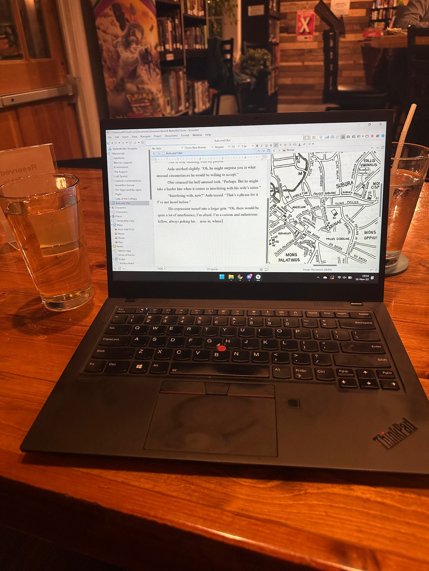 A laptop and glass of cider on a table inside a game bar