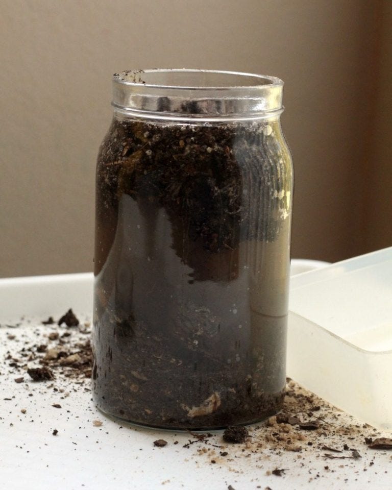 photo of sediment jar experiment - glass jar filled with mixed up dirt, water, mud, silt, etc