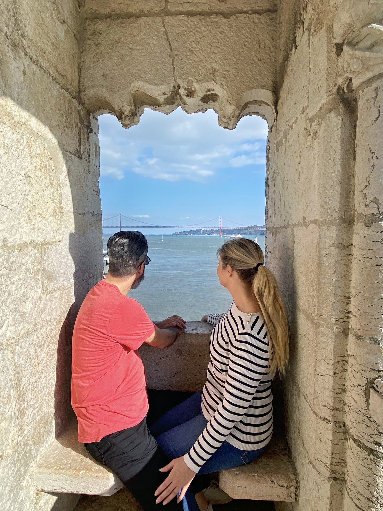 Michael and Melissa of Tourabunga peering out of the window of the Belém Tower, overlooking the river.