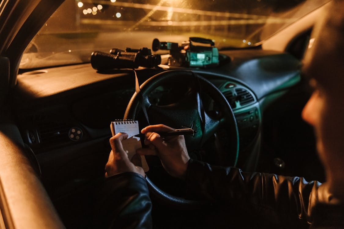 Free Journalist Taking Notes from the Crime Scene Sitting in the Car Stock Photo