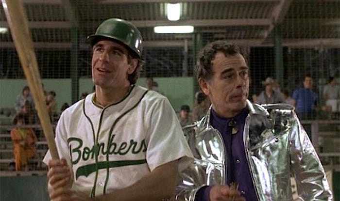 The characters Sam and Al from Quantum Leap. Sam has leapt into a baseball player. Al, a hologram projected back from the future, is invisible to everyone but Sam and wears anachronistic silver clothes.