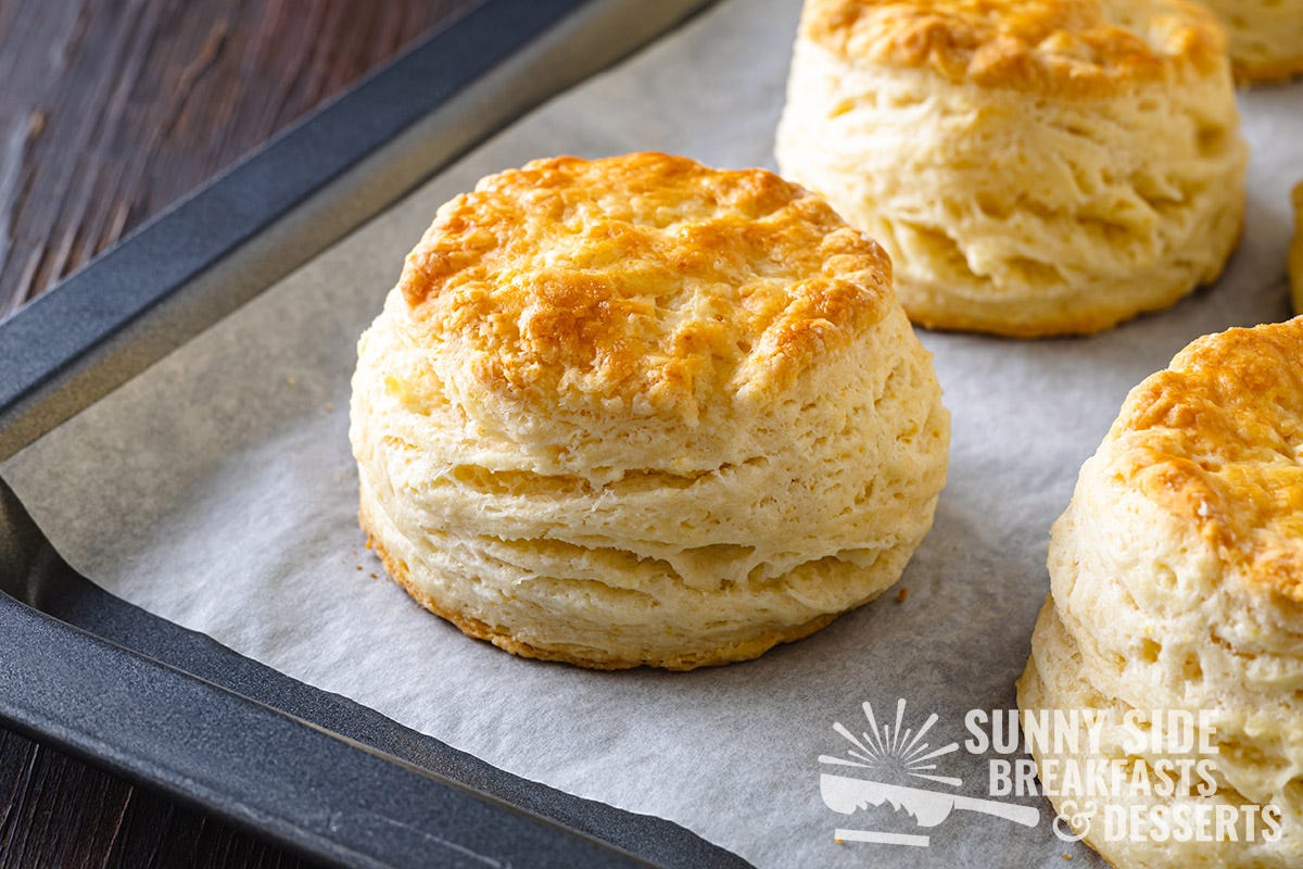 Golden cat head biscuits with flaky layers on a baking sheet.