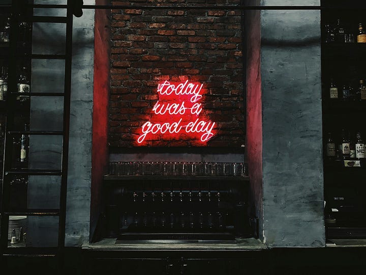 A neon sign on a brick wall. The sign reads “today was a good day.”