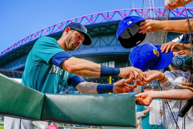 Mitch Haniger signs autographs before the start of a game against the Los Angeles Angels Friday, Oct. 1, 2021, in Seattle. (Jennifer Buchanan / The Seattle Times)