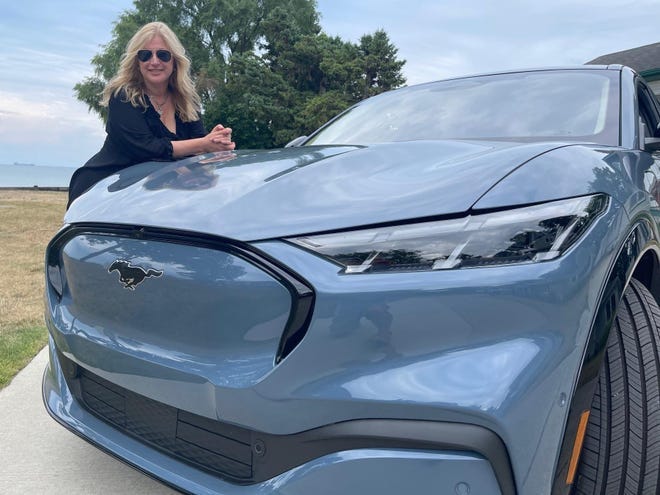 Phoebe Wall Howard stands with her new Mustang Mach-E at her favorite beach in Port Huron.