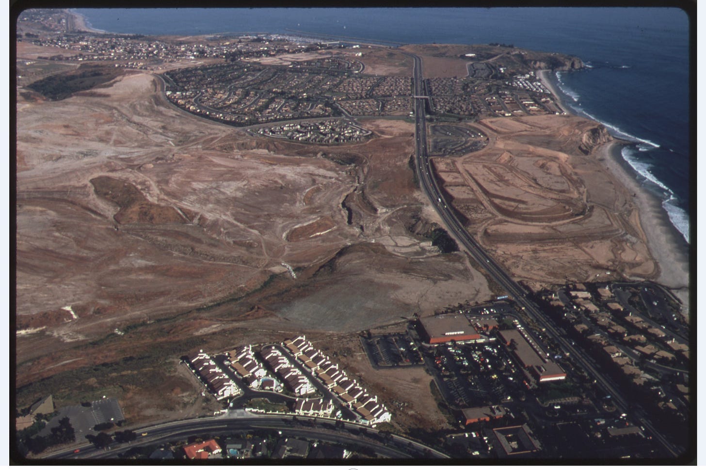 aerial view of coastal development; open space between housind developments along an ocean coast