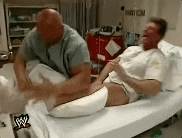 A wresting skit shows a man in a hospital bed getting punched repeatedly in the foot