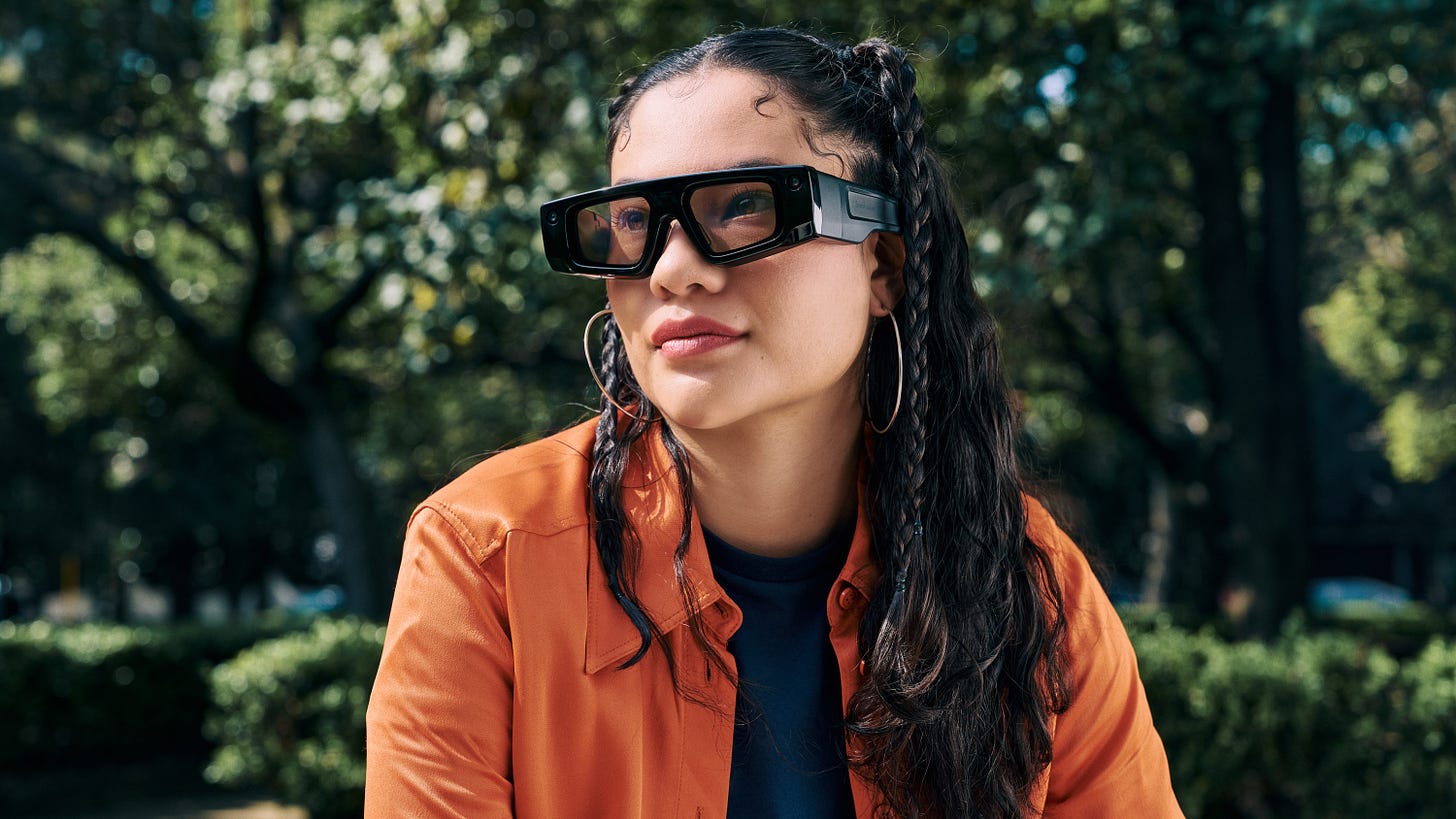 person sitting outside on a sunny day with black Snap AR glasses