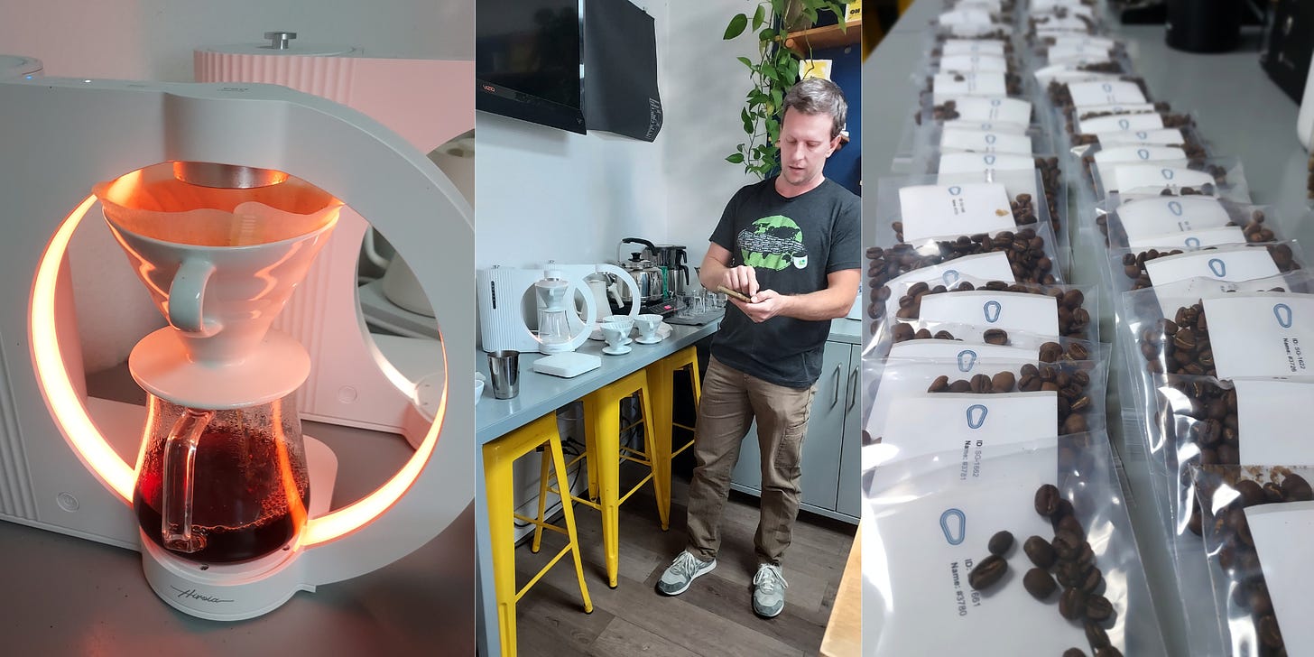 From left: A white pourover coffee brewing device with a spaceship portal essence. The glass pot filled with coffee sits on a platform under a white v60 pourover brewer with a paper filter inserted. White arms that are lit with a pulsing white light stretch up and around the coffee and brewer creating a circle. A white man taps on a phone next to the coffee brewers set on a table. Right: A long line of roasted coffee beans in small plastic sample bags with white labels stretch into the distance on a long table.