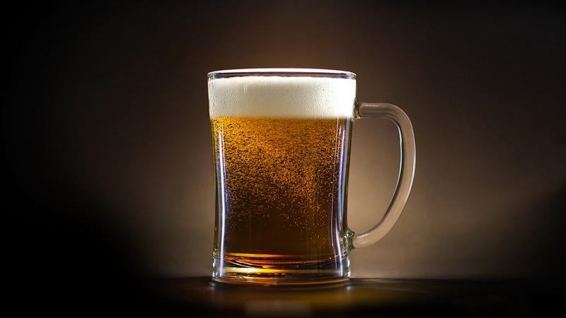 A clear glass mug full of beer against a dark background A clear glass mug full of beer against a dark background