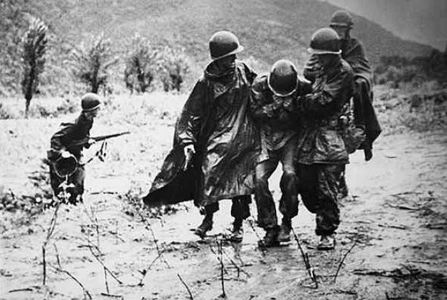 An exhausted Soldier is carried off the battlefield in Korea,