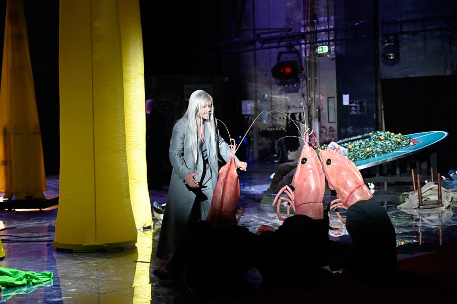 Eine Detailaufnahme von Chou En-lai mit den Garnelen und den gelben Pilzen. A man with a long grey wig (Chou En-Lei) addresses a trio of dancing shrimp.