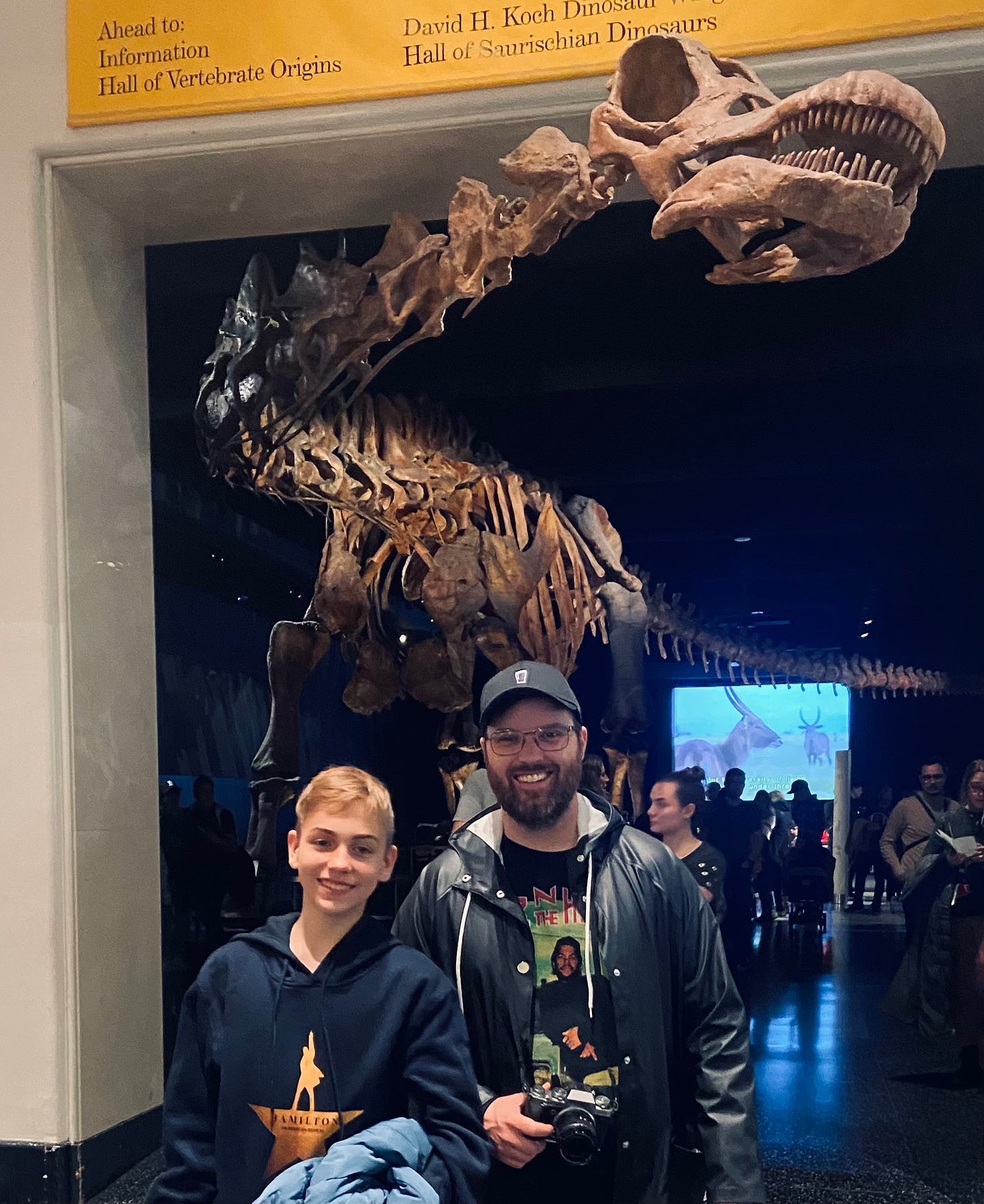 Dustin and the 13-year-old smiling in front of a dinosaur skeleton.