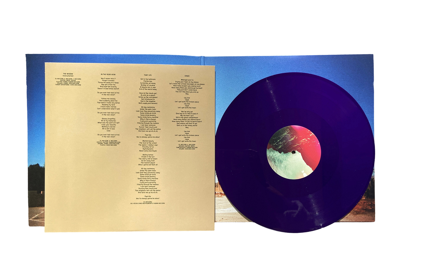 gold liner notes and a purple vinyl in front of a blue backdrop.