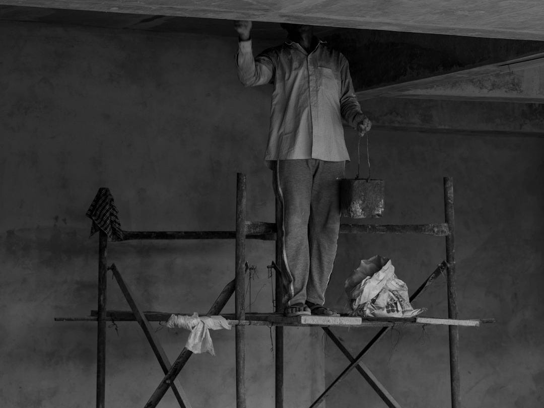 grayscale photo of man standing on ladder grayscale photo of man standing on ladder