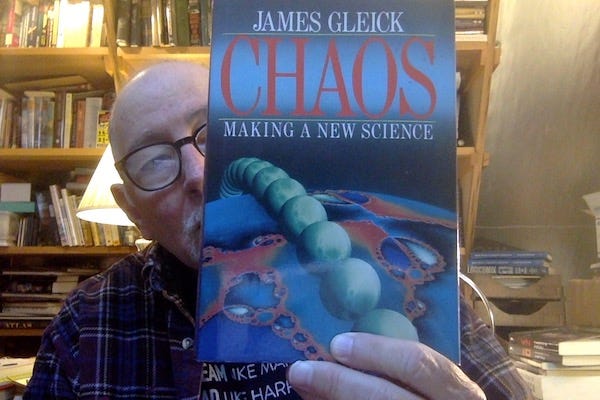 Picture of some old bald dude in his book-filled office holding a copy of Gleick's 'Chaos' to obscure most of his face.