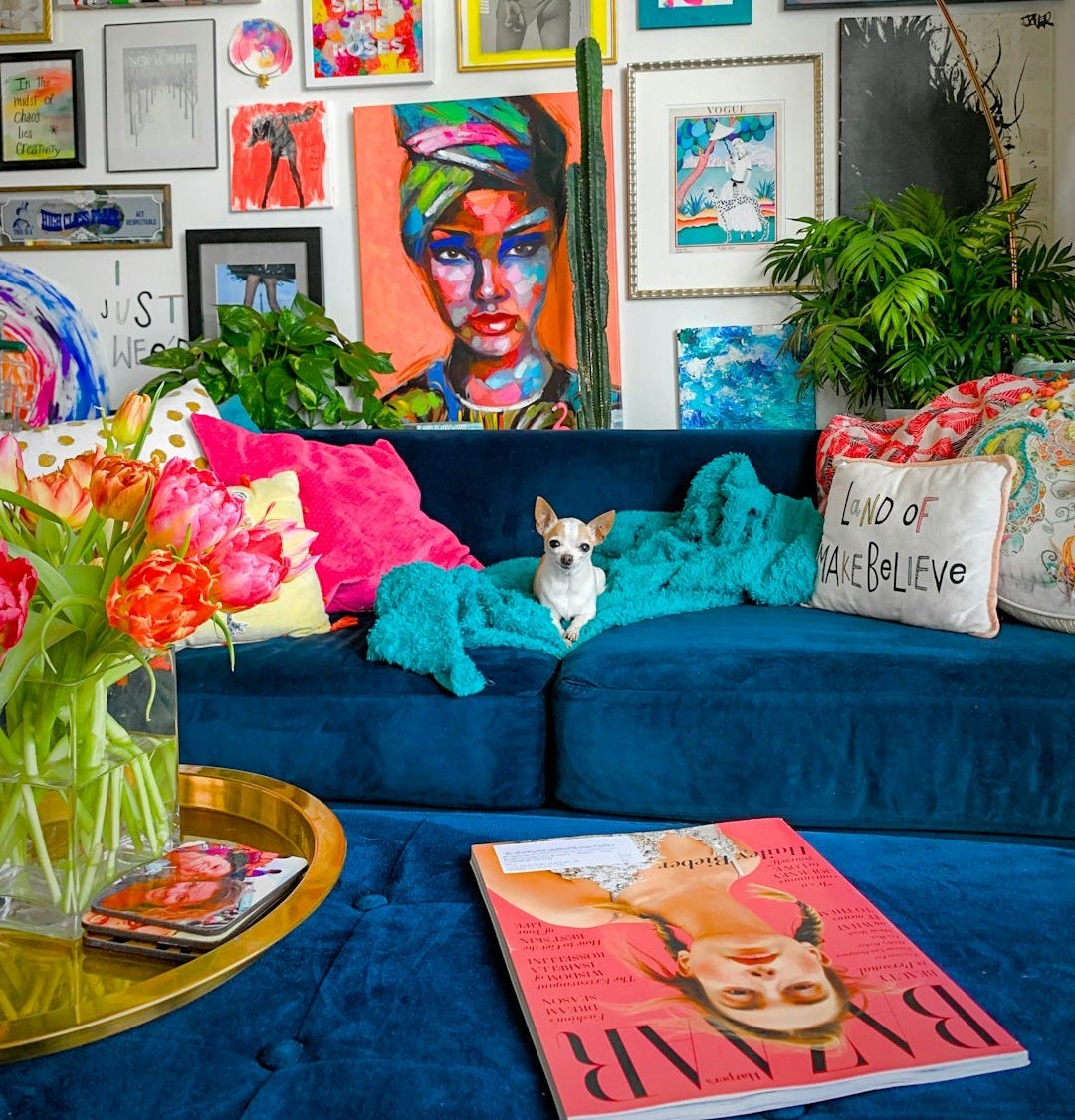 a living room filled with a blue couch and lots of pictures on the wall a living room filled with a blue couch and lots of pictures on the wall