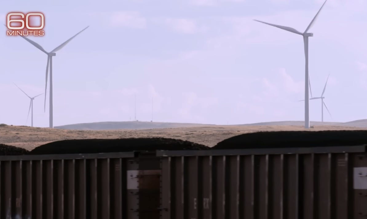CBS '60 Minutes' video screenshot showing a coal train in the foreground and a wind farm in the background