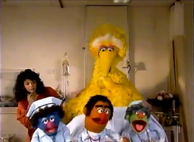 Video screenshot showing three Muppets in hospital uniforms singing in front of a bed occupied by Big Bird, as Maria looks on skeptically.