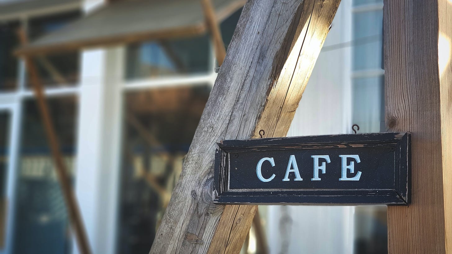 A wooden sign reading "cafe" mounted on two vertical wooden beams