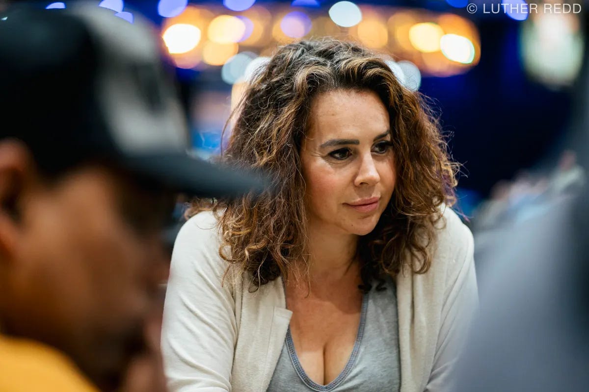 Ashira Lavine, the poker competitor, with dark shoulder length hair, grey top and white sweater. The background is blurred with lights behind her head. Photo by Luther Redd. Ashira Lavine, the poker competitor, with dark shoulder length hair, grey top and white sweater. The background is blurred with lights behind her head. Photo by Luther Redd.
