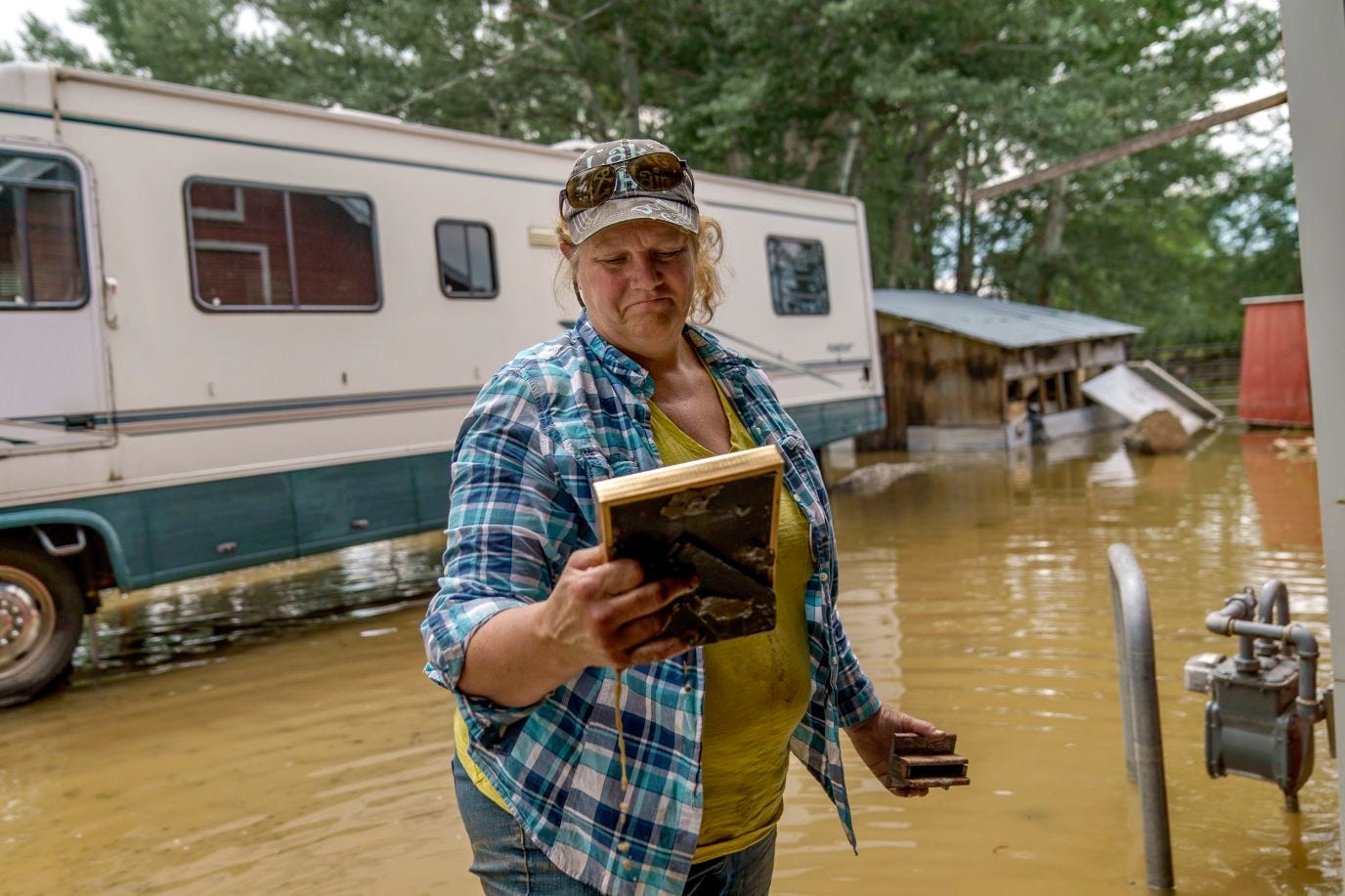 A woman stares sadly into a photograph as she stands in floodwaters.