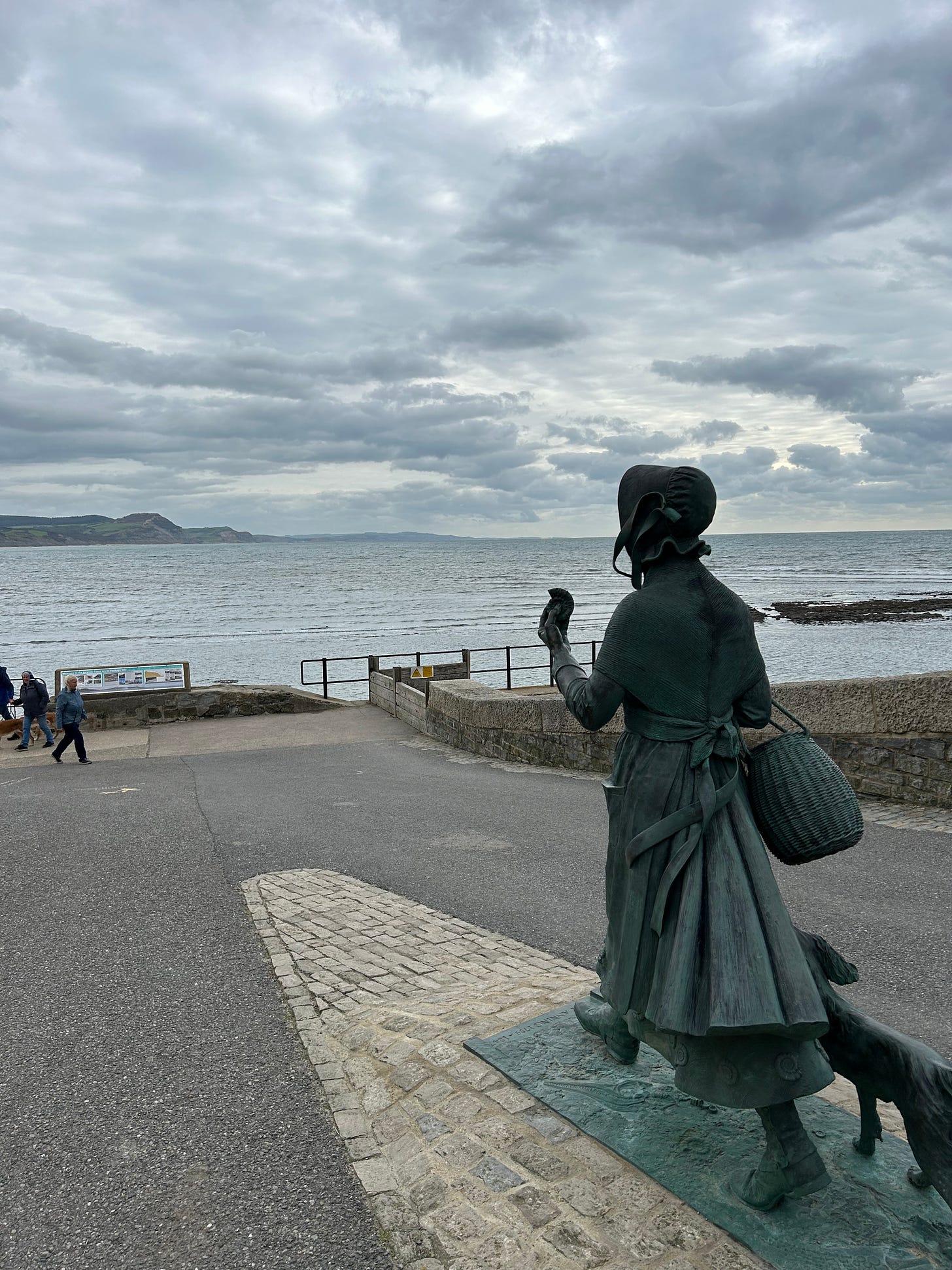 Mary Anning looks east across the bay at some of the fossil-rich coastline. The grey sky gives a dramatic look to the photo. Image: Roland’s Travels