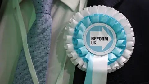 Reuters Um observador do partido Reform UK usa uma roseta