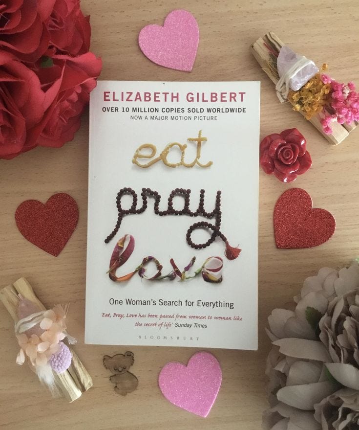 This may contain: the book eat pray love is surrounded by flowers and other crafting supplies on a table