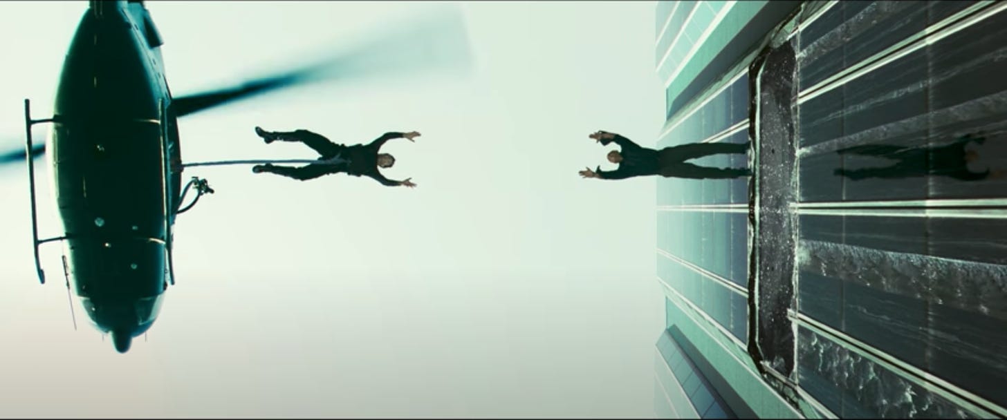 A screenshot from The Matrix. Neo leaps from a helicopter to catch Morpheus, who's leaping from a building. They're caught in a frozen moment, both in midair.