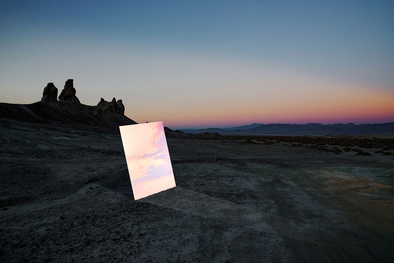 A mirror in the desert reflects the sunset