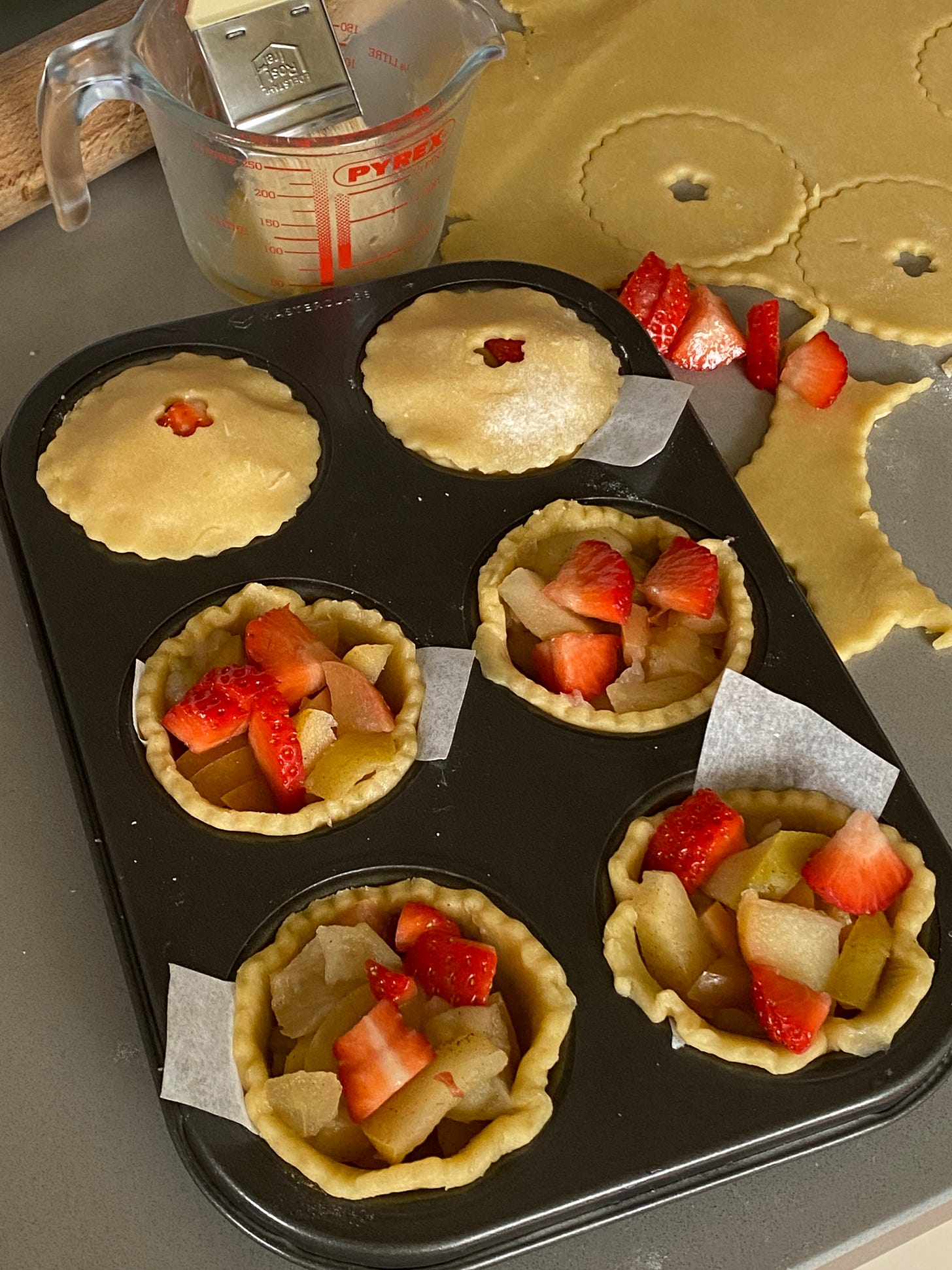 six unbaked fruit pies in a baking tray.