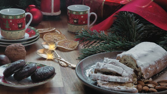 A table filled with treats, decorations, and two Christmas mugs. A pair of golden flares shines off two spoons.