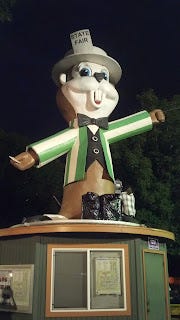 A large statue of a gopher dressed up in a blazer and hat on top of a building.