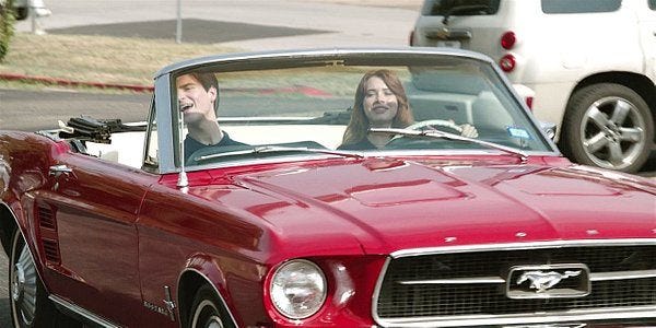 Walker Augie and Stella in red Mustang convertible.