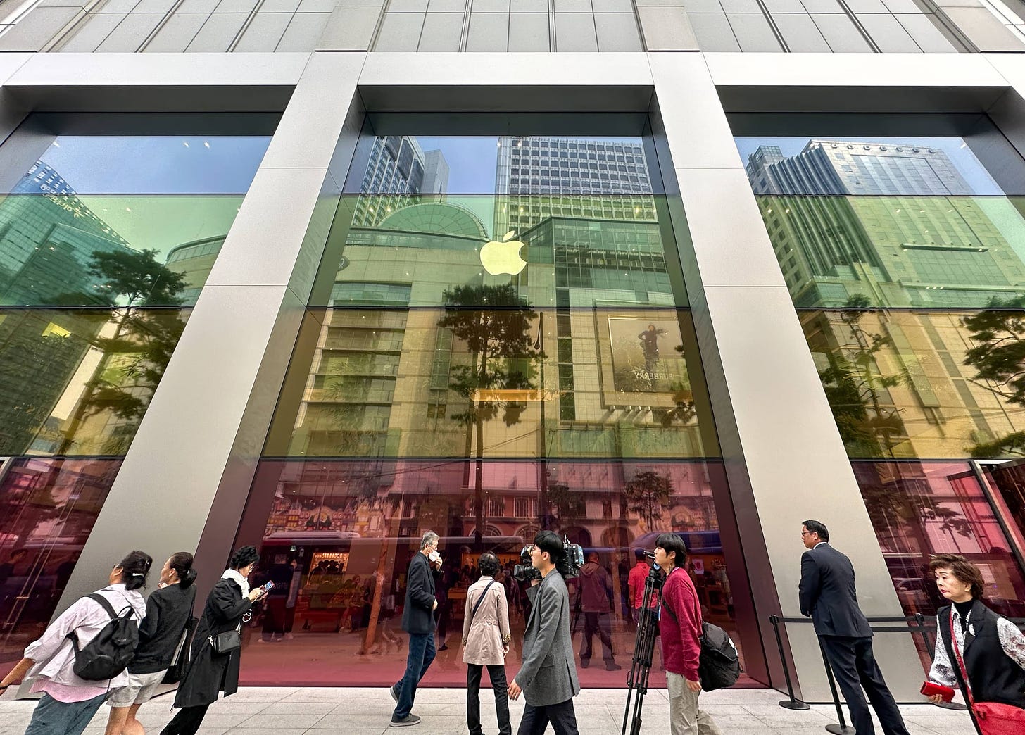 The facade of Apple Myeongdong. The windows are covered with horizontal bands of color matching the finishes of iPhone 15.