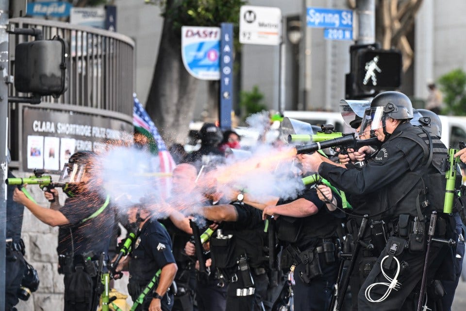 LA police officers firing less-lethal weapons at protesters.