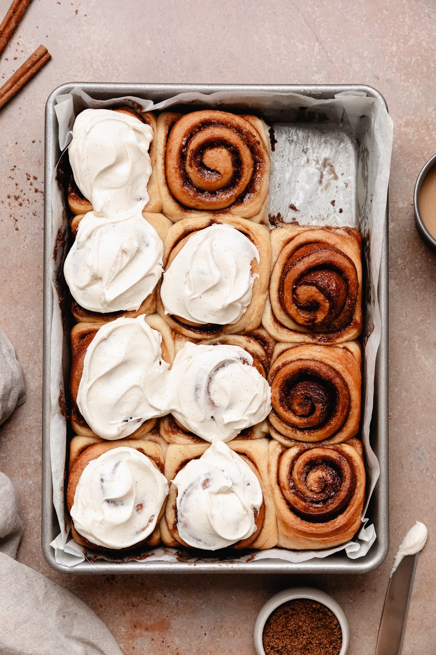 Vegan cinnamon rolls with cream cheese frosting seen from the top in a pan