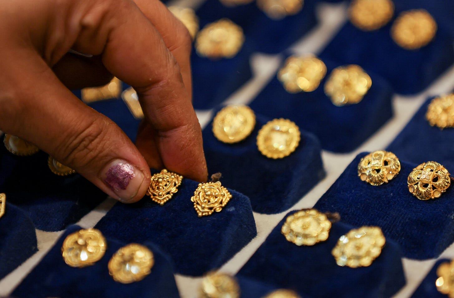 A woman picks a gold earring at a jewellery shop in the old quarters of Delhi