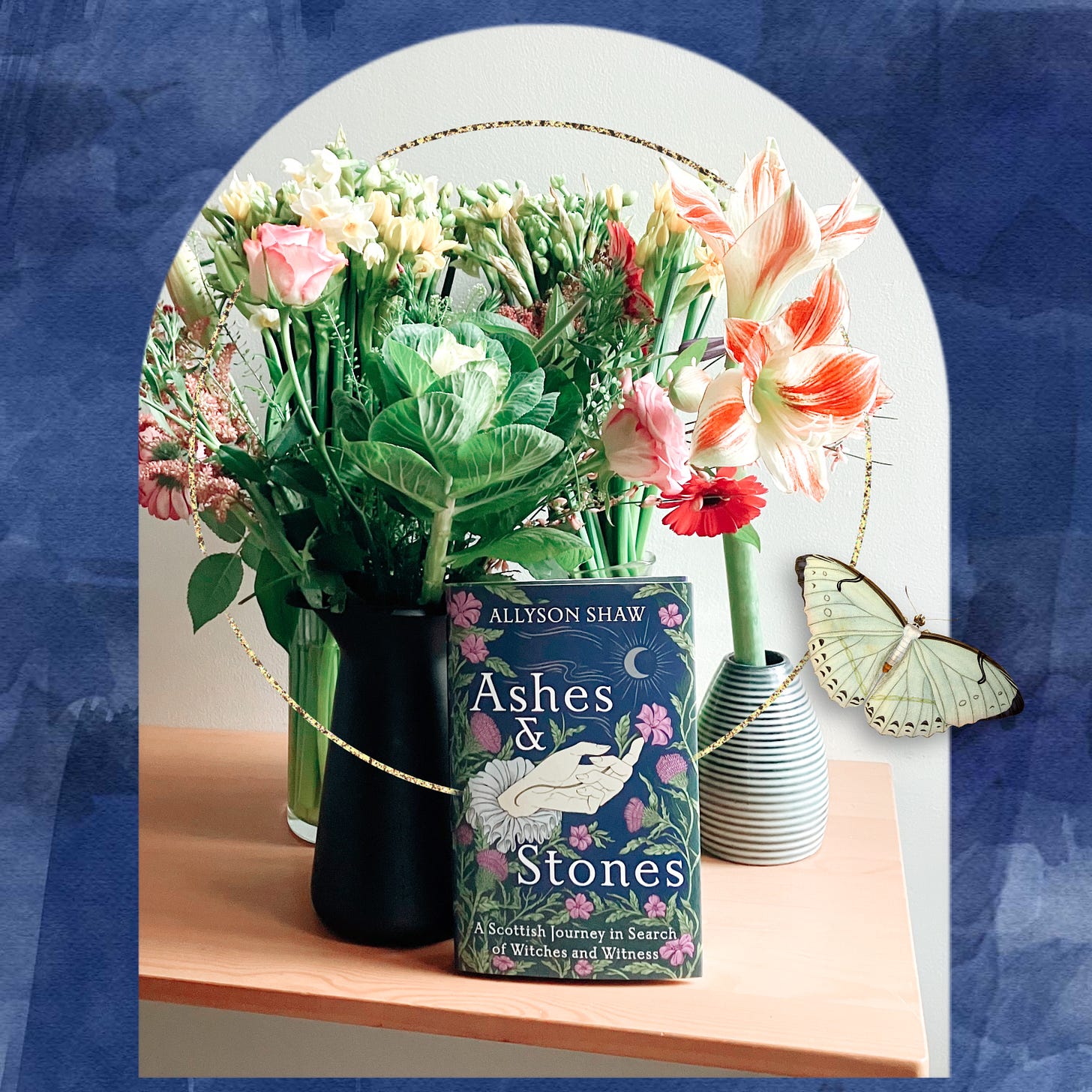 Digital collage of flowers in vases on a tabletop a copy of the book Ashes and Stones, gold glitter and a butterfly over a blue watercolour background.