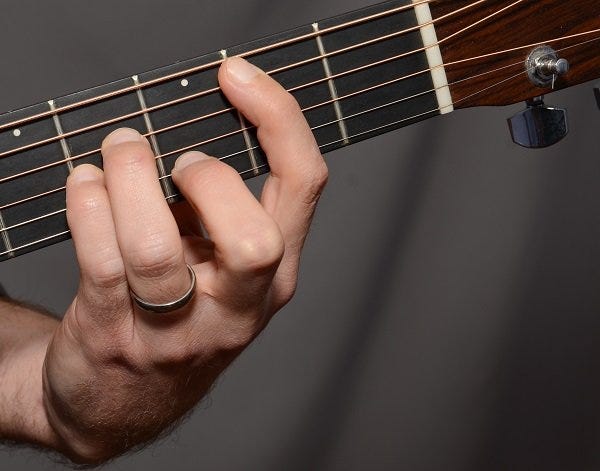 Close up of teacher showing hand position for common bar-chord